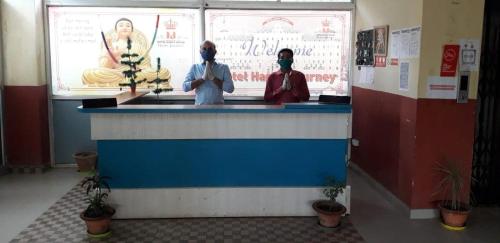 two people wearing face masks standing at a counter at OYO Hotel Happy Journey in Dīgha