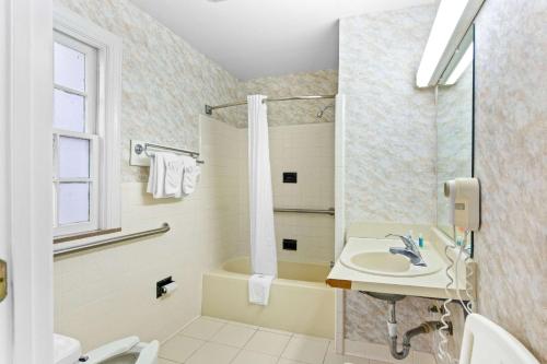 y baño con lavabo, ducha y bañera. en Rodeway Inn Historic, en Williamsburg