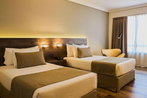 um quarto de hotel com duas camas e uma cadeira em Dazzler by Wyndham Buenos Aires San Martin em Buenos Aires