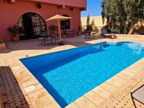 a blue swimming pool in front of a house at Les Villas de Nouran 7chambres in Ghazoua