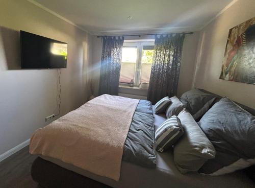 een bed in een slaapkamer met een raam en een televisie bij Ferienwohnung Feldblick in Schwerin
