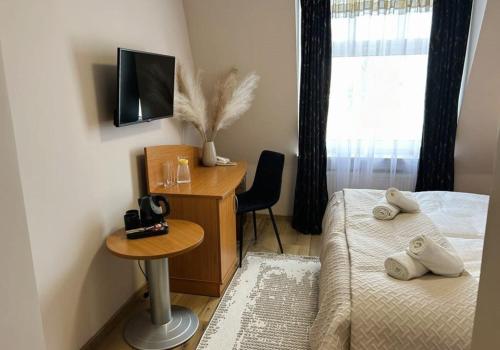 a bedroom with two beds and a desk with a television at Motel Petro in Torzym