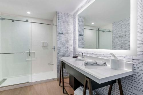 a white bathroom with a sink and a shower at Cambria Hotel Austin Downtown in Austin