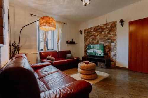 ein Wohnzimmer mit einem Ledersofa und einem TV in der Unterkunft Cozy getaway house Luana in Buzet