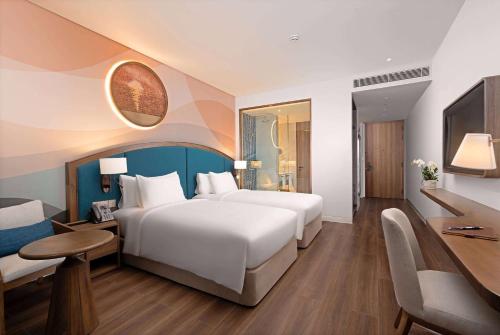 a hotel room with a large bed and a desk at Wyndham Garden Sonasea Van Don in Cái Rồng