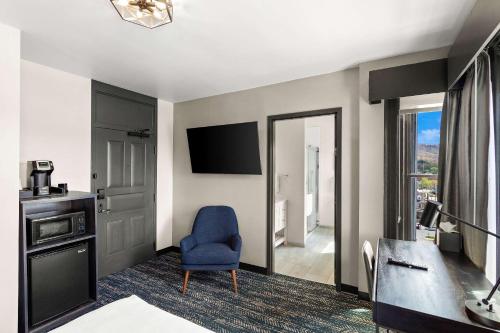 um quarto de hotel com uma cadeira azul e uma televisão em Tygart Hotel, Ascend Hotel Collection em Elkins