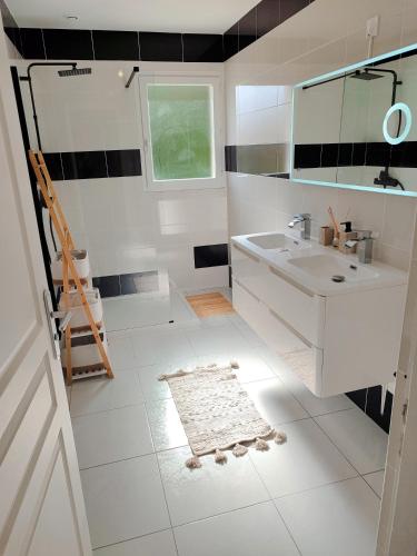 une salle de bain blanche avec un lavabo et un miroir dans l'établissement Maison contemporaine, à Floirac