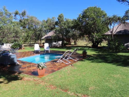 a backyard with a swimming pool with two lawn chairs at Marico Guest Lodge in Groot-Marico