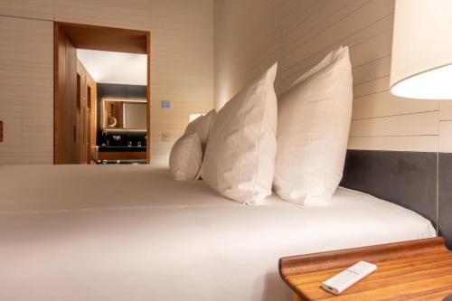 a bed with white pillows and a remote control on it at Atrio in Cáceres