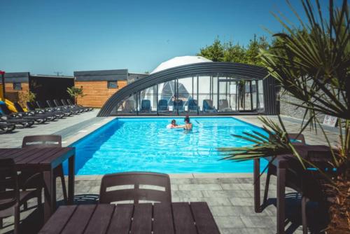 a swimming pool with two people in the water at RResort Holiday Homes - HEATED Swimming Pool & Sauna in Rewal