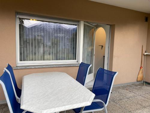 una mesa blanca y sillas azules frente a una ventana en Muralto-Locarno: Miramonti Apt. 4, en Locarno