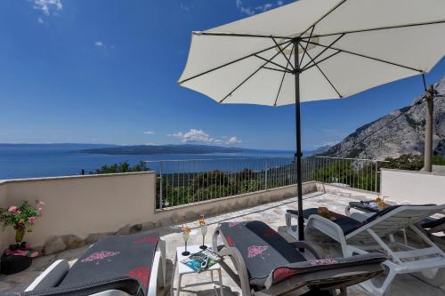 a patio with chairs and an umbrella and the ocean at Holiday home Marta with heated pool,grill,sea view in Bast