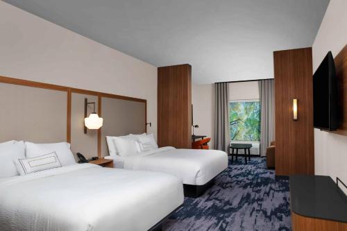 a hotel room with two beds and a flat screen tv at Fairfield by Marriott Inn & Suites Lewisburg in Lewisburg