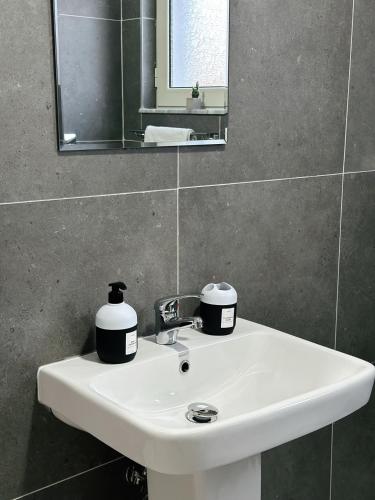 Js House Shkoder 3 في شكودر: حوض غسيل أبيض في حمام مزود بمرآة