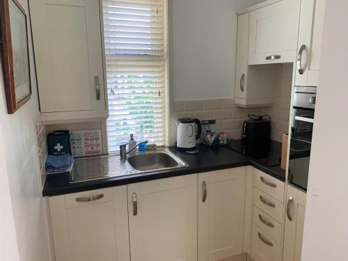 a kitchen with white cabinets and a sink at Old School Apartment 1 First Floor in Bury Saint Edmunds