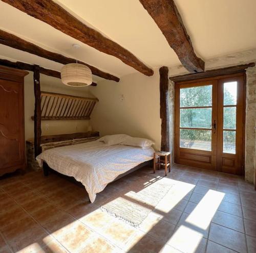 une chambre avec un lit et une grande fenêtre dans l'établissement Maison de caractère avec piscine 1h de Toulouse, à Saint-Cirq