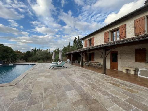un patio avec un banc à côté d'un bâtiment dans l'établissement Maison de caractère avec piscine 1h de Toulouse, à Saint-Cirq
