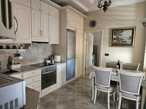 Una cocina con gabinetes blancos y una mesa y sillas. en Zemun Center LUX 3 bedroom, en Belgrado
