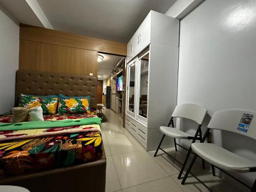 a room with two beds and chairs in it at Shell Residence MOA Manila by JO Alano in Manila