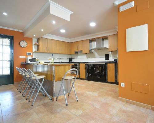 a kitchen with orange walls and a counter with stools at GALIHOST - Casa da Sobreira in Meis