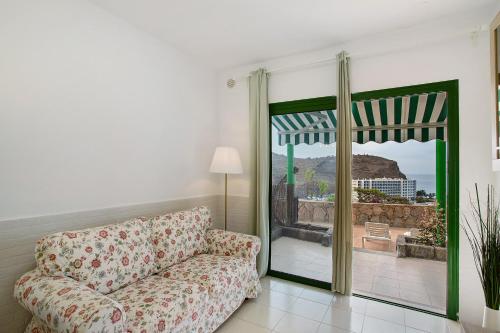 a living room with a couch and a sliding glass door at Casa Los Veleros F1 in Puerto Rico de Gran Canaria