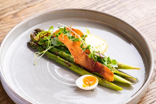 a plate of food with an egg and asparagus at The White Horse Hotel, Romsey, Hampshire - The Coaching Inn Group in Romsey