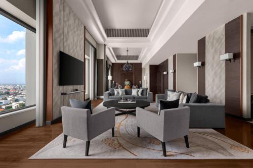 a living room with a couch and chairs and a tv at Chiang Mai Marriott Hotel in Chiang Mai