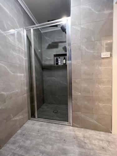 a shower with a glass door in a bathroom at Morisset Cottage Blackheath in Blackheath