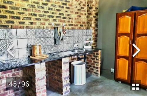 a bathroom with a counter and a brick wall at Midvaal Guesthouse in Meyerton