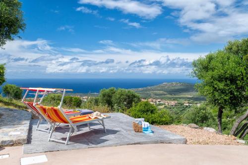 a chair sitting on a rock with a view of the ocean at Sa Domo Isola Rossa in Trinità dʼAgultu