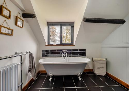ein Bad mit einer großen Badewanne und einem Fenster in der Unterkunft Cwtch Honey in Lampeter