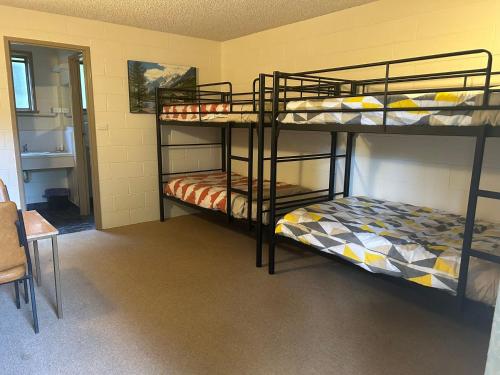 ウォーバートンにあるgreen gables warburton student camper accomodationの二段ベッド2台とテーブルが備わる客室です。