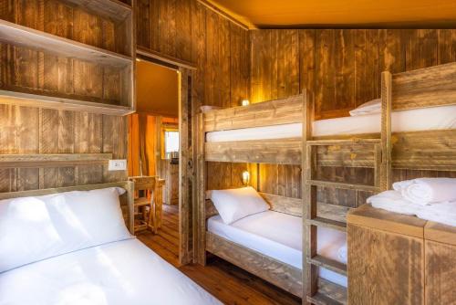 Luxury Lodge Glamping في Palazzolo dello Stella: سريرين بطابقين في غرفة مع جدران خشبية