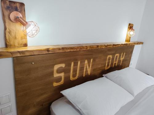 a bed with a wooden headboard with a sun cut on it at Sun Day Apartments Free Airport Shuttle in Artemida