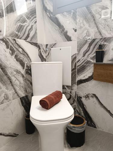 a bathroom with a toilet with a towel on it at Sun Day Apartments Free Airport Shuttle in Artemida