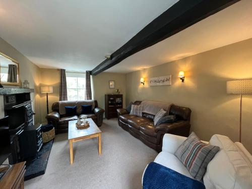 a living room with leather couches and a table at Wensleydale Stone Cottage in Hunton