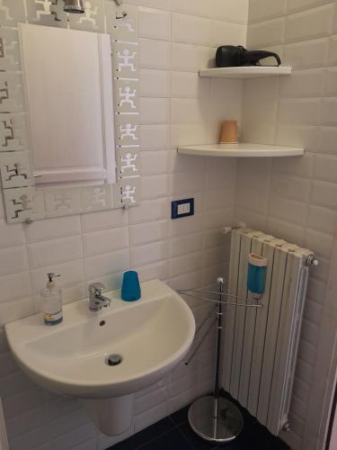 uma casa de banho branca com um lavatório e um espelho em "B&B Sans égal", con camere private e appartamenti al piano terra a Biella em Biella