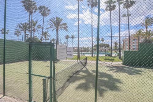 a batting cage behind a fence with palm trees at Las Americas in Islantilla