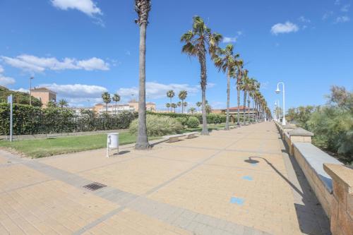 a sidewalk with palm trees in a park at Las Americas in Islantilla