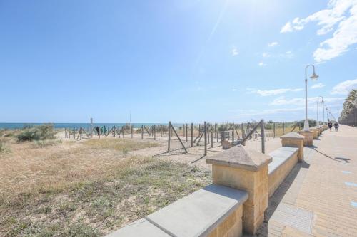 a row of stone benches next to a beach at Las Americas in Islantilla
