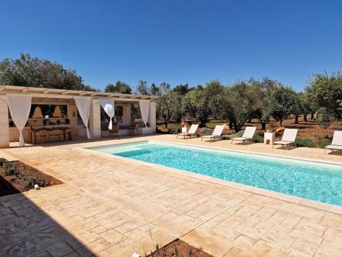 a swimming pool with a gazebo and chairs around it at Trulli Tramontana - private pool in Ostuni