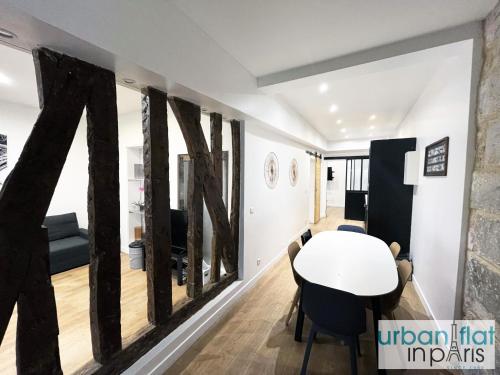 une salle à manger avec une table et un mur avec de grandes fenêtres dans l'établissement Urban Flat 52 - Charming 2 BDR Flat in Center of Paris, à Paris