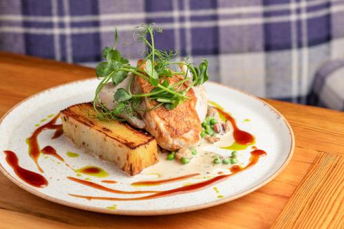 a plate of food with bread and vegetables on a table at The Pheasant Hotel, Holt, Norfolk - The Coaching Inn Group in Kelling