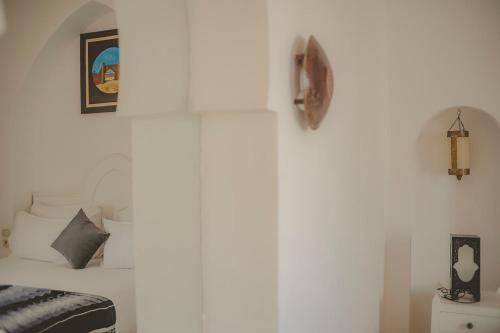 ein weißes Schlafzimmer mit einem Bett und einer Uhr an der Wand in der Unterkunft Palais Des Remparts in Essaouira