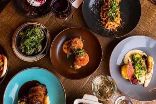 a wooden table with plates of food on it at The Pheasant Hotel, Holt, Norfolk - The Coaching Inn Group in Kelling