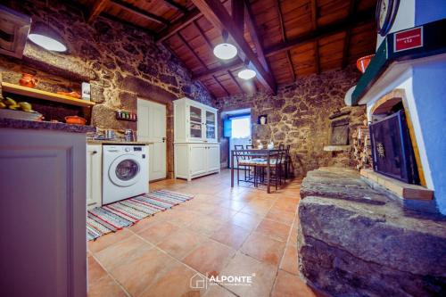 uma cozinha com máquina de lavar e secar roupa num edifício de pedra em Refugio dos Cartolas em São Mamede