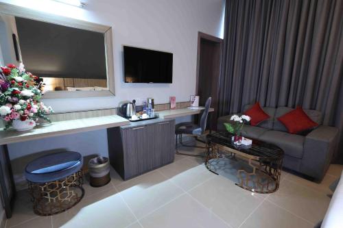 a room with a couch and a desk in a hotel room at Fortis Hotel Fujairah in Fujairah
