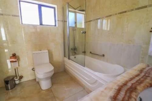 Rosenia Boutique Hotel 20792 Block 3 في غابورون: حمام مع مرحاض وحوض استحمام ومغسلة