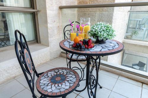 a table with fruit and drinks on a balcony at Isrentals Haneviim - ApartHotel In City Center in Jerusalem
