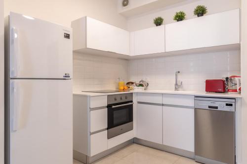 a kitchen with white cabinets and a refrigerator at Isrentals Haneviim - ApartHotel In City Center in Jerusalem